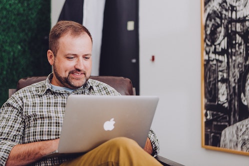 person sat down on mac laptop